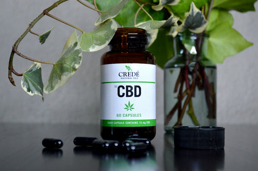 a bottle of cbd sitting next to a vase of flowers